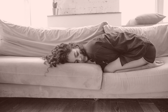femme recroquevillée en position ventrale sur un canapé